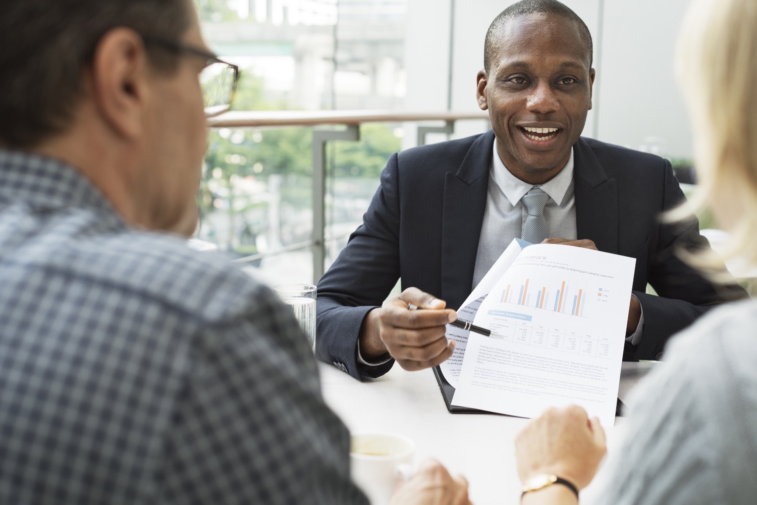 Well dressed man reviews financial data with a couple for Prudential Wellness Wednesday