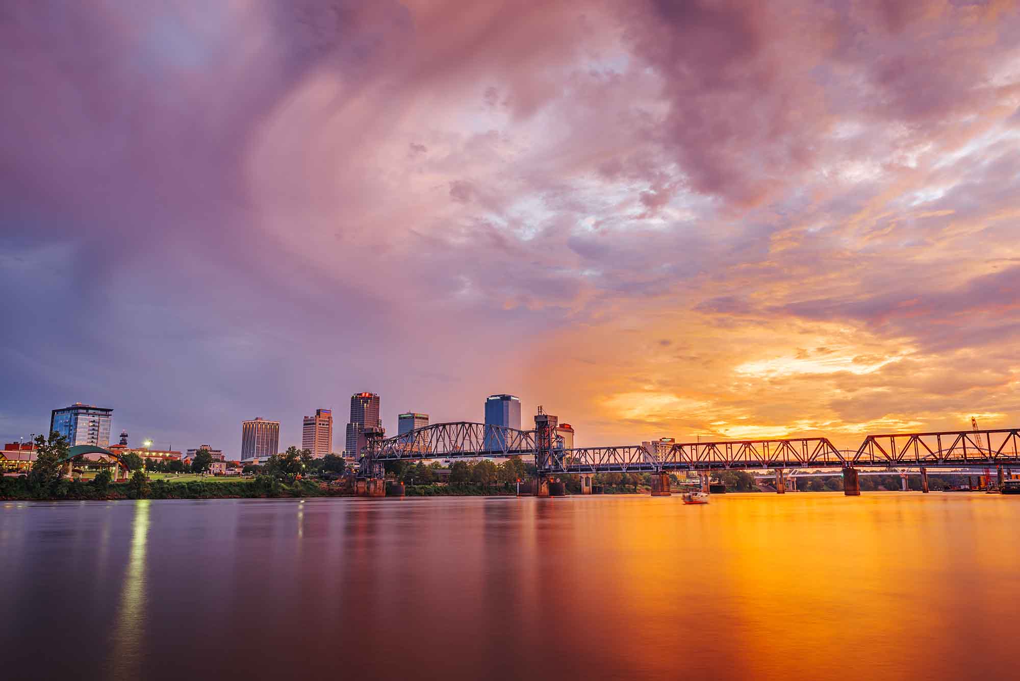 Little Rock skyline at sunset with orange and pink hues across the sky.