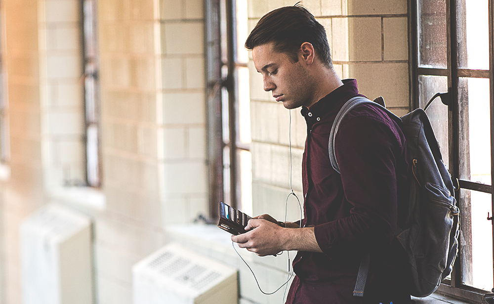 Main looking at a cell phone in a hallway.