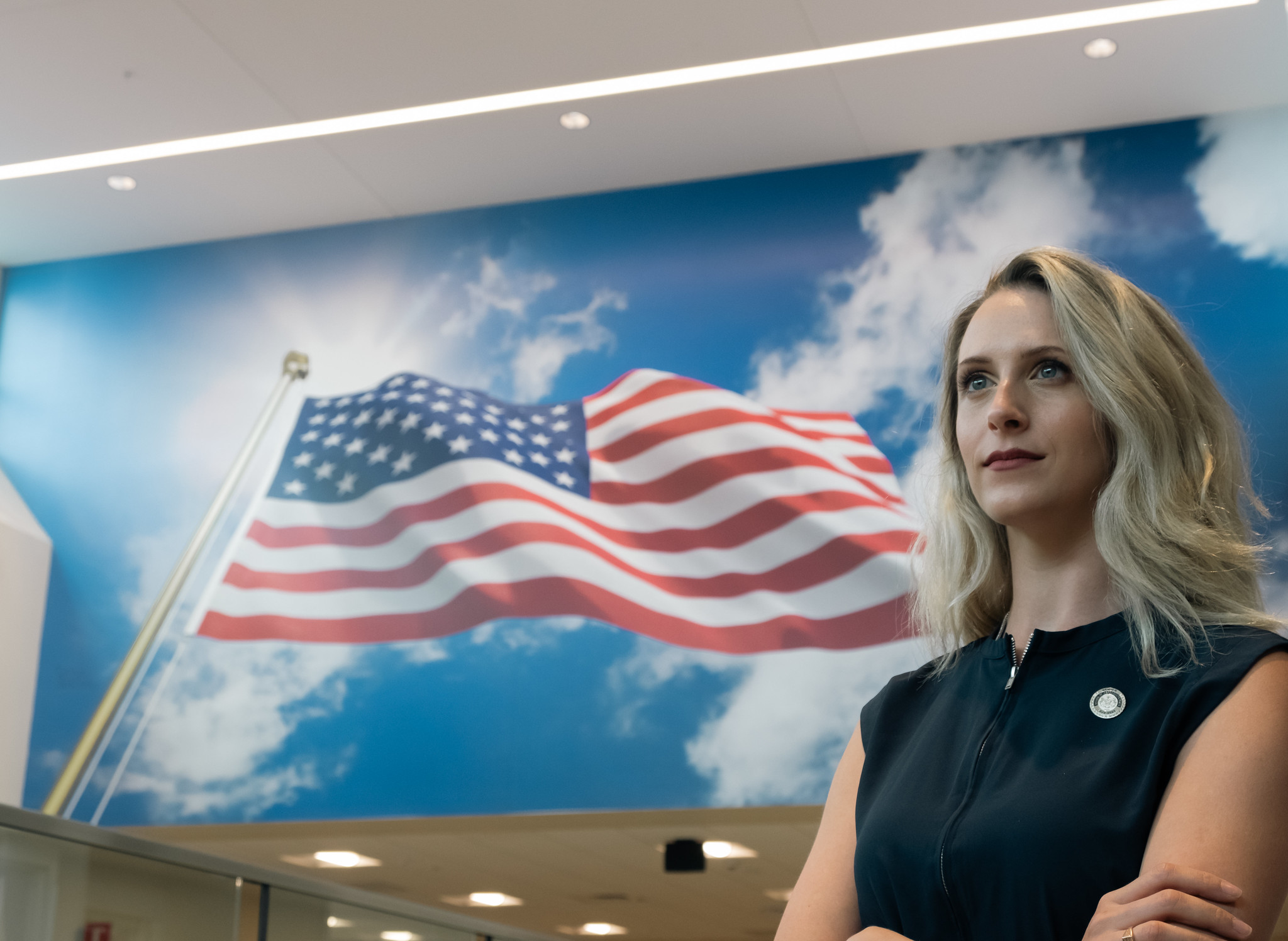 VA Staff member standing in front of a mural that feature the flag of the United States of America.